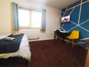a bedroom with a bed and a desk and a window at Bankwell Guest House in Manchester