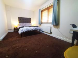 a bedroom with a bed and a window with blue curtains at Bankwell Guest House in Manchester