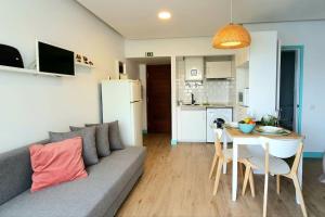 a living room with a couch and a table and a kitchen at Apartamentos do mar in Funchal
