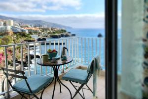 a balcony with a table and chairs and a view of the ocean at Apartamentos do mar in Funchal