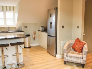 a kitchen with a refrigerator and a chair at Orchard Apartment in Shrewsbury