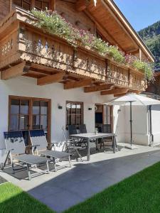 a patio with a table and chairs and a balcony at Hochalmbahnen Chalets Rauris 1-08WE1, Maislaufeldweg 1e EG in Rauris