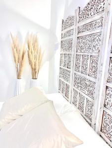 una camera da letto con un letto bianco e due vasi con piante di L’Escale - Le Boho + garage + NETFLIX a Saint-Étienne
