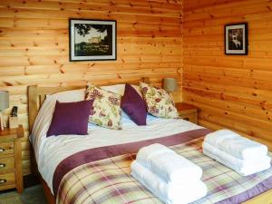 um quarto com uma cama num chalé de madeira em Red Kite & Osprey Lodges em Rhilochan