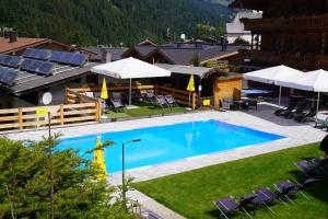 een buitenzwembad met stoelen en parasols bij Hotel Aschauer Hof z'Fritzn in Kirchberg in Tirol