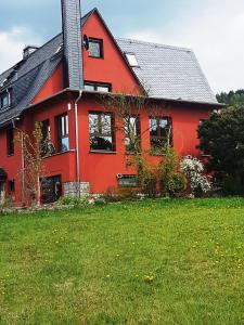 une maison rouge avec une pelouse verte devant elle dans l'établissement Montanregion Erzgebirge-Ihr Urlaub ist unsere Herzenssache, à Langenberg