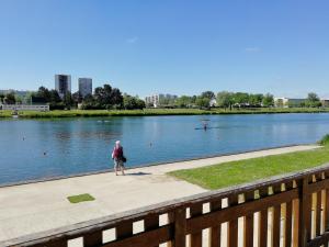 une personne se promenant sur un trottoir à côté d'un lac dans l'établissement LOUE MAISON ENTIÈRE PROPRE ! Endroit calm, à 5 minutes gare mantes la jolie, à Mantes-la-Jolie