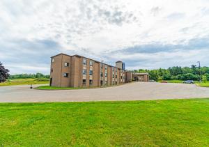 a building on a road with a grass field at Slumber Inn in New Minas