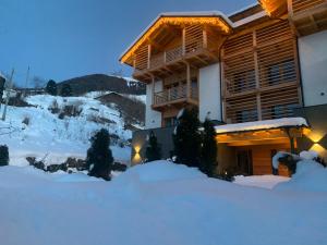 a ski lodge in the snow at night at Affittacamere Casa Ester in Baselga di Pinè