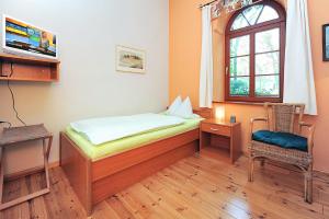 a bedroom with a bed and a window and a chair at Pension Altes Posthaus in Dangast