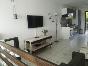 een woonkamer met een tafel en een televisie aan de muur bij Happy Residence - Orient Beach 09 in Saint Martin