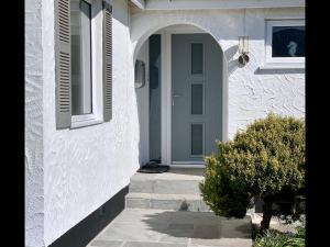 a white house with a blue door and a bush at Bungalow33 Benllech in Benllech