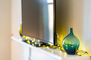 a blue glass vase sitting on a shelf in front of a television at Manor Place in Broughty Ferry