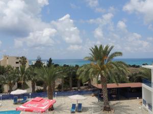 a view of a resort with palm trees and the ocean at West End Hotel in Peyia
