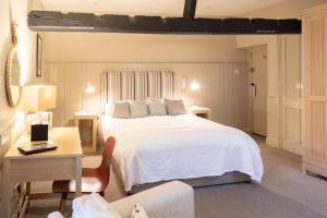 a bedroom with a white bed and a desk and a chair at The White Horse Blakeney in Blakeney