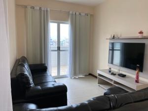 a living room with a leather couch and a television at Cobertura Duplex Algodoal in Cabo Frio