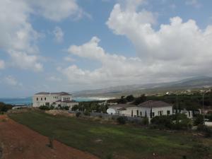 a house on a hill with the ocean in the background at West End Hotel in Peyia