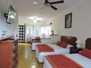 a hotel room with two beds and a flat screen tv at Hotel El Moro in Puerto Morelos