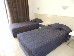 a hotel room with two beds and a window at West End Hotel in Peyia