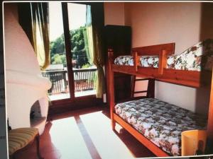 a bedroom with two bunk beds and a balcony at Villa Olga Lago Maggiore in Castelveccana