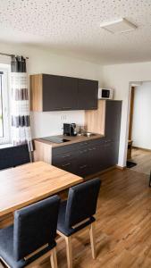 a kitchen with a wooden table and black cabinets at Apartment am Alpakahof Hahn in Grafenschlag