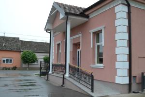 a pink house with a balcony in a street at Sobe Sova Kikinda in Kikinda