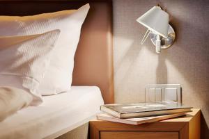 a bed with a night stand with a lamp and books at homie hotel wiener botschaft in Veitshöchheim