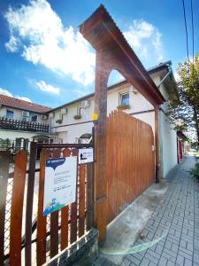 una valla de madera junto a una casa con un cartel en Hargita Panzio, en Vecsés