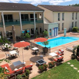 een terras met tafels en parasols en een zwembad bij Mercure Castres L'Occitan in Castres