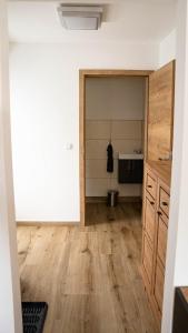 an empty room with a kitchen with wooden floors at Apartment am Alpakahof Hahn in Grafenschlag