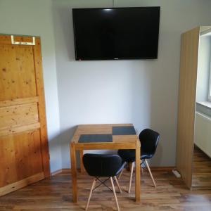 a table with two chairs and a television on a wall at Auerandzimmer in Nienhagen +1 photo