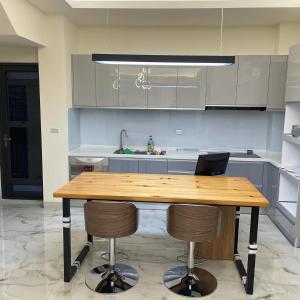 a kitchen with a wooden table and two bar stools at Rebecca Hostel in Chaozhou