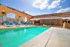 una piscina con sedie a sdraio blu accanto a un edificio di Hotel Caribe Merida Yucatan a Mérida