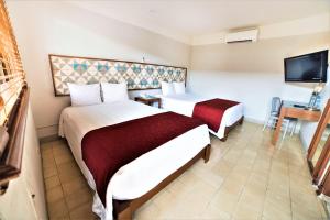 una camera d'albergo con due letti e una televisione di Hotel Caribe Merida Yucatan a Mérida