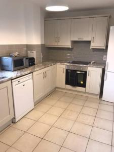 a kitchen with white cabinets and a black microwave at Tinnins Cottage in Newry