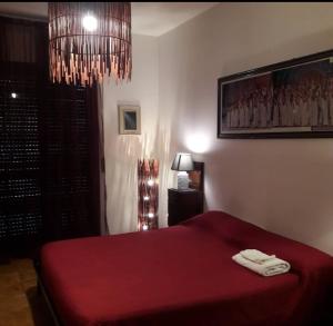 a bedroom with a red bed and a chandelier at Casa Trastevere in Foggia