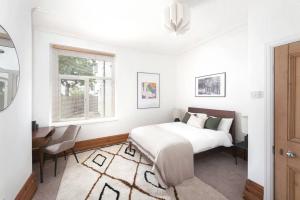 a white bedroom with a bed and a window at Relax in Stunning Apartment In Leafy Victorian Area in Cardiff