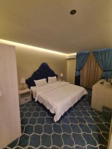 Schlafzimmer mit einem großen Bett mit blauem Kopfteil in der Unterkunft روز نيري 2 in Khobar