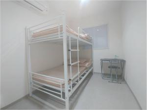 ein weißes Etagenbett in einem Zimmer mit einem Schreibtisch in der Unterkunft Simple Stay Miyajima in Hatsukaichi