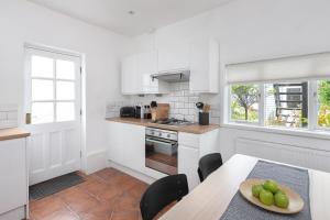 uma cozinha com armários brancos e uma mesa com uma taça de fruta em Relax in Stunning Apartment In Leafy Victorian Area em Cardiff