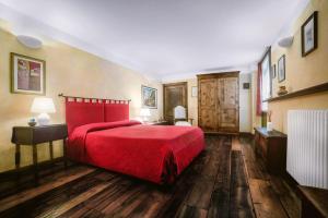 アオスタにあるB&B Al Nabuissonのウッドフロアのベッドルーム1室(赤いベッド1台付)