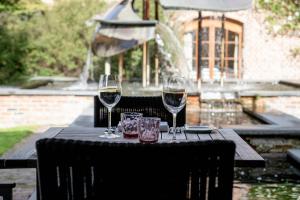 Ein Tisch mit zwei Weingläsern und einem Brunnen in der Unterkunft Hostellerie De Biek in Moorsel