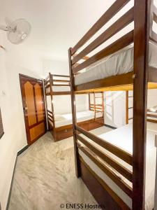 a room with three bunk beds and a door at Eness Hostels Pondicherry in Puducherry