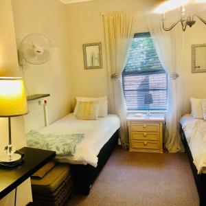 a small bedroom with two beds and a window at Wellington Country House in Wellington