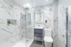 a white bathroom with a toilet and a shower at Minster's Reach Apartments -Stylish City-Centre Retreat's in York +50 photos