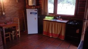 a kitchen with a refrigerator and a table and a sink at Alto Valle Cabañas de Montaña in Mina Clavero +8 photos