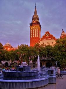 a building with a clock tower with a fountain in front of it at MB Apartment 2 in Subotica