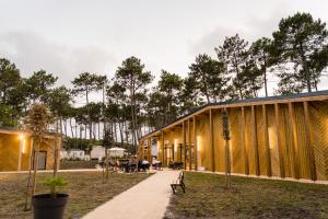 un gran edificio de madera con árboles en el fondo en Camping Les dunes de Contis chez Nelly&Thomas, en Saint-Julien-en-Born