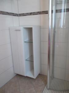 Ferienwohnung Jürges في نورتهايم: خزانة بيضاء في الحمام مع دش