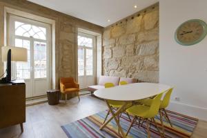 a living room with a table and chairs and a clock at RVA - Clerigos Apartments in Porto